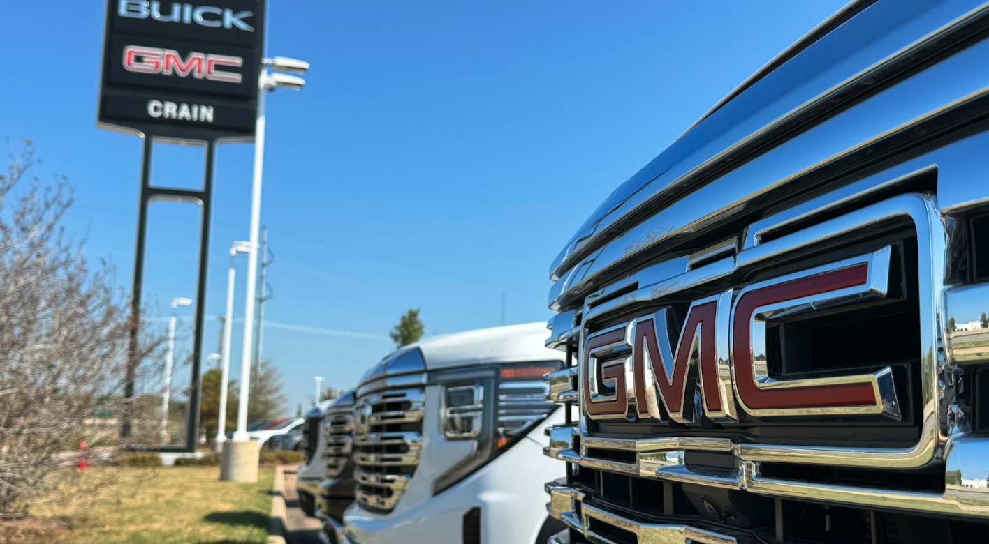 Close-up of GMC truck grille with Crain Buick GMC dealership sign in the background in Conway, Arkansas
